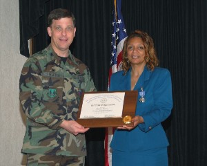 Col. Kenneth Fielding, USAF, presents a plaque of appreciation to Debra Foster at the May farewell celebration marking her transition of duty station.
